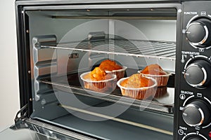 Electric mini oven and baked hot muffins close up photo