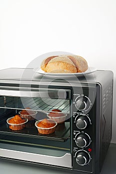 Electric mini oven and baked hot muffins close up photo