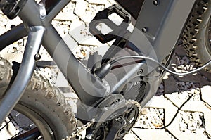 Electric mountain bike is charging, with the plug inserted to recharge the battery. Detail.