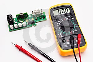 Electric multimeter with red and black probe, display indicating zero, with printed circuit board. Isolated on a white background