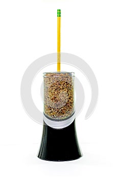 Electric pencil sharpener with a yellow pencil sticking out of it, filled to the brim with pencil shavings, isolated on