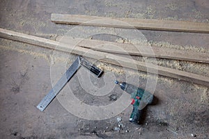 Electric perforator with drill is on the dirty and dusty wooden floor during under renovation, remodeling and construction