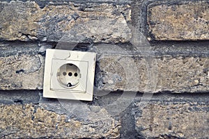 Electric plug connector, ac outlet, on brick wall.