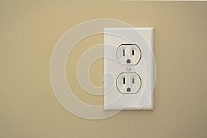 Electric plug connector (outlet) on a beige wall