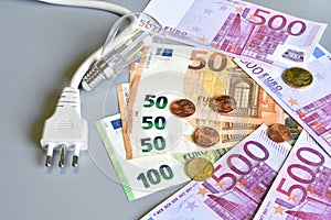 Electric plug, euro money banknotes and cents with light bulb over grey background. Concept for the increase of electricity cost.