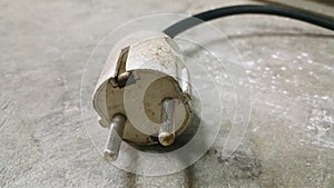 Electric plug on workshop floor. Electric European plug. White power cable with plug. Power cord close-up