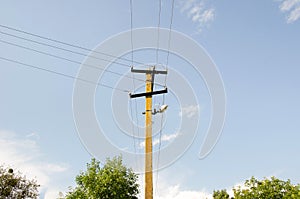 Electric pole power lines outgoing electric wires againts on cloud blue sky.