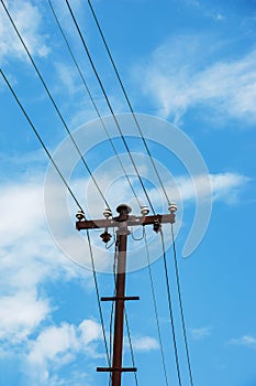 Electric pole power lines outgoing electric wires againts on cloud blue sky