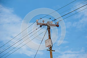 Electric pole power lines outgoing electric wires againts on cloud blue sky