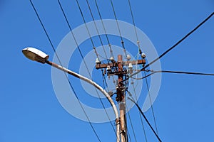 Electric pole power lines outgoing electric wires againts on cloud blue sky