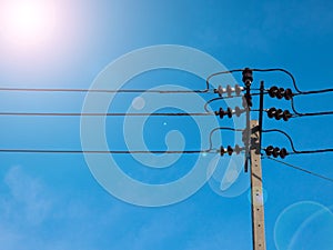 Electric pole power lines and wires with blue sky with lamp.