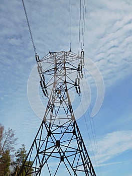 Electric pole of transmission line against a blue sky and white clouds