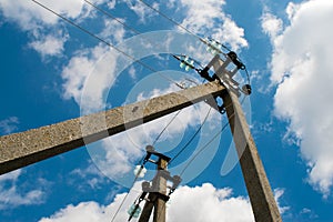 Electric pole with wires against a blue sky with clouds