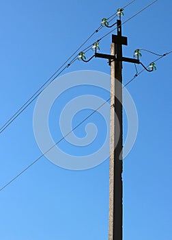 Electric pole with wires and insulators against blue sky