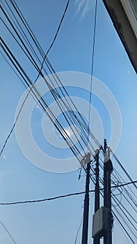 Electric poles and cabels against a blue sky background