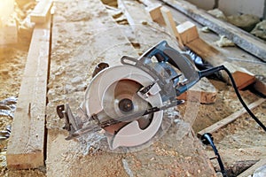 electric portable circular saw is on wooden board in house under construction of foam block