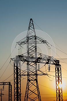 Electric post with wires with sunset background. Transmission tower. Power lines on a colorful sunset. Close up high