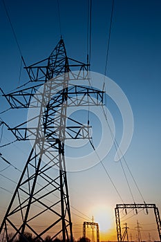 Electric post with wires with sunset background. Transmission tower. Power lines on a colorful sunset. Close up high