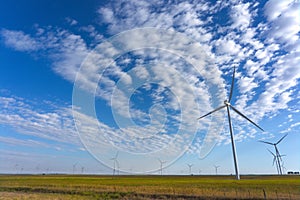 electric power generating mills in a green field with blue sky and some clouds