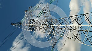 Electric power lines and pylon against blue sky. Vertical video. Electric tower