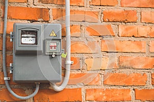 Electric power meter measuring power usage. Watt hour electric meter measurement tool on brick wall