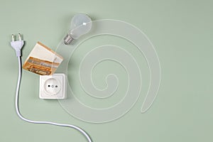 Electric power plug, light bulb and electric socket with Euro banknotes on light green background. Electricity cost and