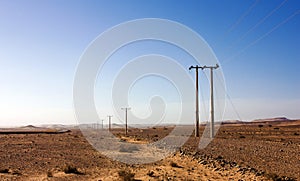 Electric power poles in desert of Jordan, high voltage powerlines, early morning in wilderness.
