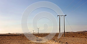 Electric power poles in desert of Jordan, high voltage powerlines, early morning in wilderness.