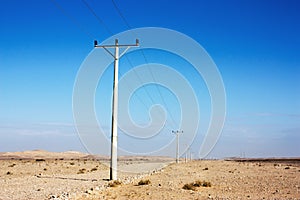 Electric power poles in desert of Jordan, high voltage powerlines, early morning in wilderness.