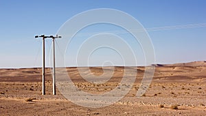 Electric power poles in desert of Jordan, high voltage powerlines, early morning in wilderness.