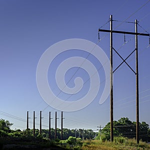 Electric power poles, pylons and transmission lines over the meadow photo