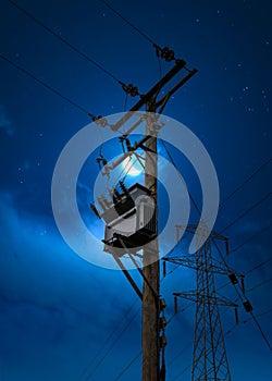 Electric power pylon cables at night blue hour crescent moon sky. High voltage electricity substation on wooden pole tower