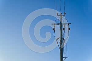 electric power sky lines and connections on a wooden post. wooden electricity post against blue sky. Electric power lines and