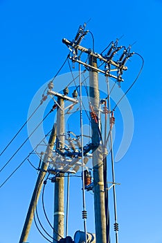 electric power sky lines and connections on a wooden post. wooden electricity post against blue sky. Electric power lines and