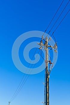 electric power sky lines and connections on a wooden post. wooden electricity post against blue sky. Electric power lines and