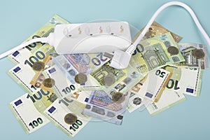 Electric power strip extension cord and Euro money banknotes on light blue background. Rising electric price and