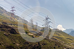 Electric power towers along mountain terrain during day.