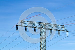 Electric power transmission concept. Selective focus on a electricity supply pylon and the high voltage power lines against a blue