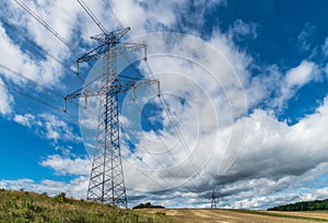 Electric power transmission line in nature scenery with blue sky and beautiful white clouds