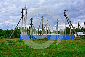 Electric Power Transmission Lines over trees. High voltage line and electrical substation on the background of trees and sky