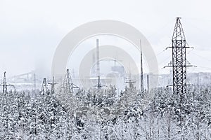 An electric power transmission lines from power station passes in wintry forest, snowy wires