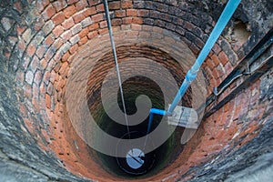 Electric pump in the groundwater well with water in the bottom