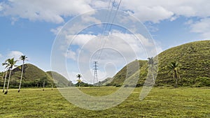 An electric pylon runs High voltage lines through the Chocolate Hills in Bohol. Power distribution concept