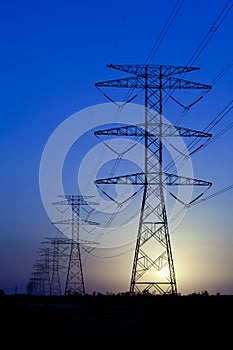 Electric Pylons against blue sky with sun