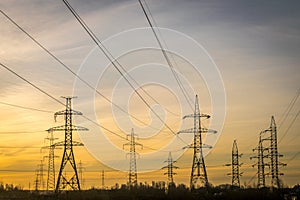 Electric pylons with cables and wires at dawn or dusk.