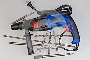 Electric rotary hammer and different drill bits on gray background