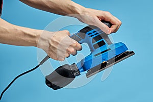 Electric sanding machine for home handyman use, on blue background