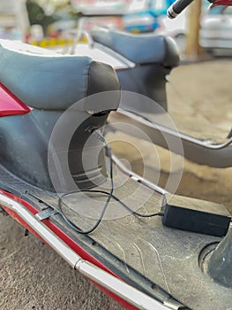 An electric scooter charging with cable plugged in to it
