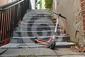 an electric scooter lying at the bottom of a flight of stairs