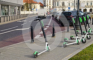 Electric scooter parked on the road. Modern eco electric city scooters for rent outdoors on the sidewalk. Alternative transporte. photo